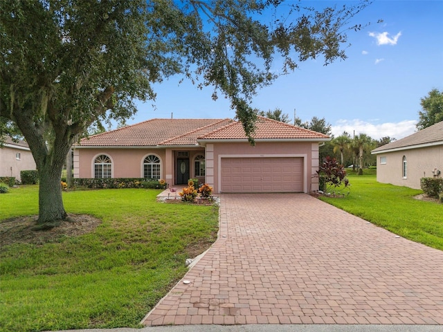 view of front of house with a front lawn, a tiled roof, decorative driveway, and stucco siding