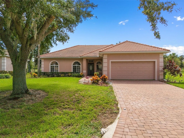 view of front of house with a front yard, decorative driveway, a tile roof, and stucco siding