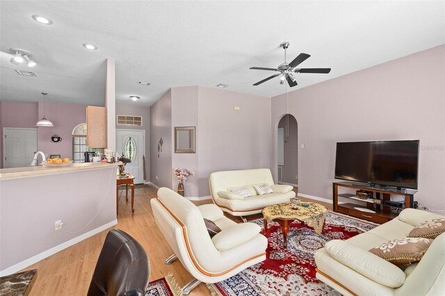 living room featuring light wood-type flooring, ceiling fan, and sink