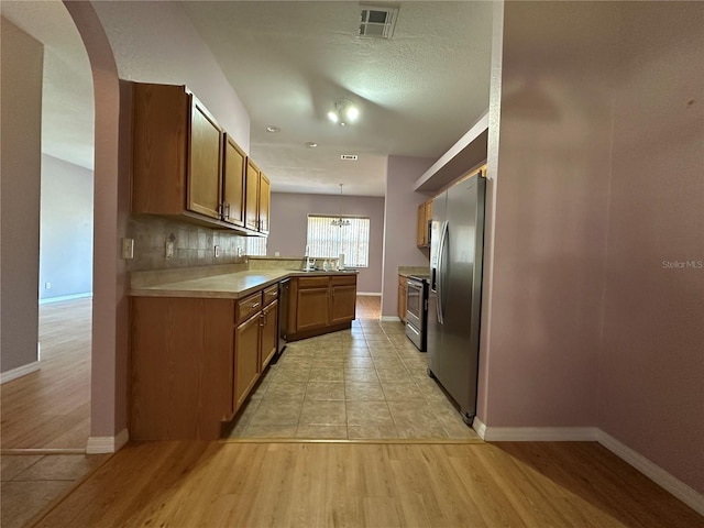 kitchen featuring light hardwood / wood-style floors, appliances with stainless steel finishes, hanging light fixtures, sink, and kitchen peninsula