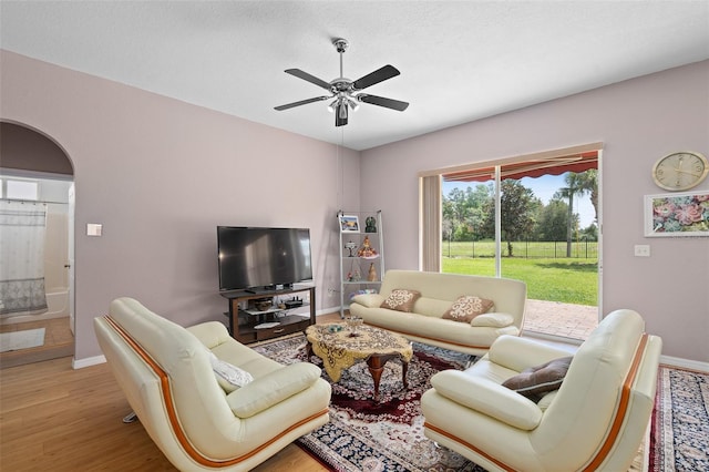 living room with ceiling fan, a textured ceiling, and light hardwood / wood-style flooring