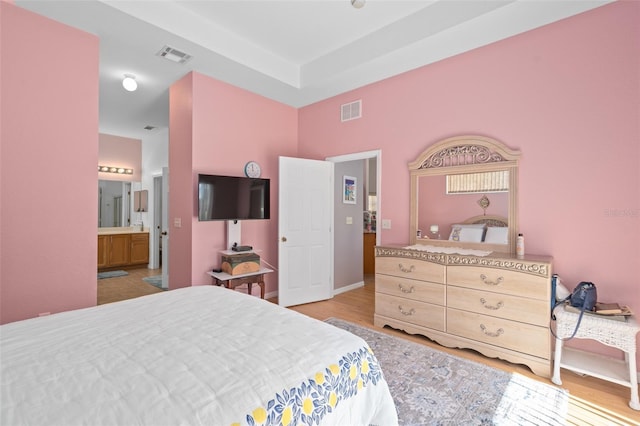 bedroom featuring light wood-type flooring and connected bathroom