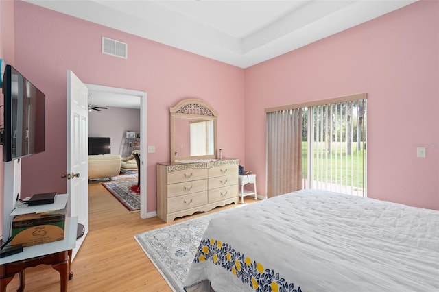 bedroom with a raised ceiling and light hardwood / wood-style flooring