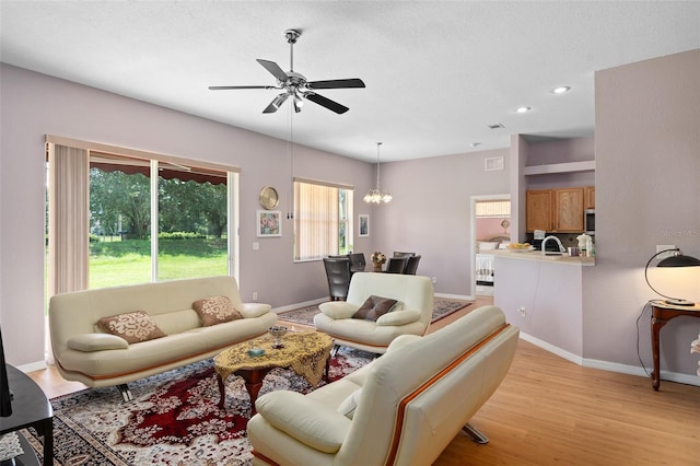 living room featuring light hardwood / wood-style floors and ceiling fan with notable chandelier