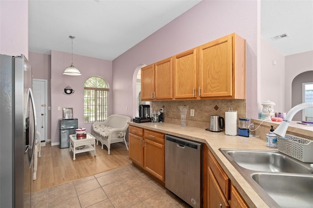 kitchen with sink, decorative light fixtures, backsplash, light tile patterned floors, and stainless steel appliances