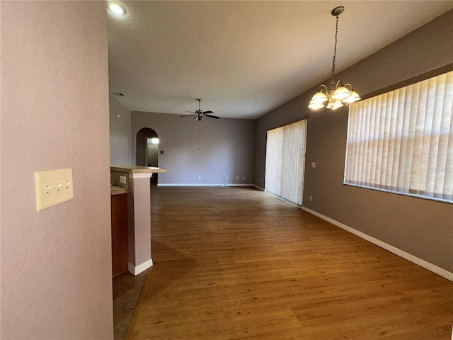 unfurnished dining area featuring ceiling fan with notable chandelier and dark hardwood / wood-style flooring