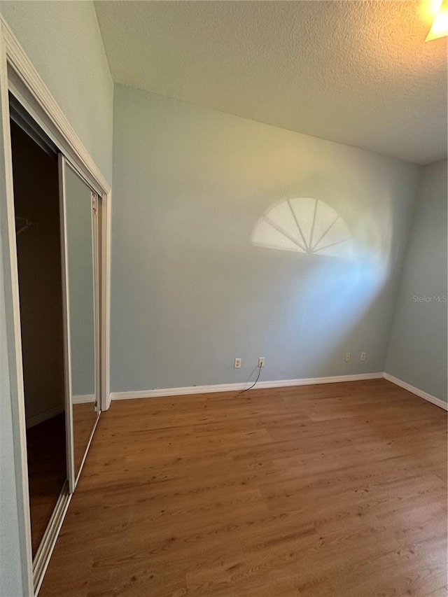 unfurnished bedroom with wood-type flooring, a closet, and a textured ceiling