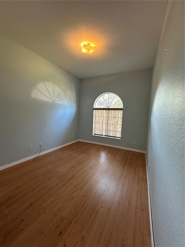 empty room with hardwood / wood-style flooring and a textured ceiling