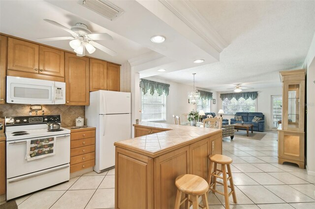 kitchen with white appliances, a ceiling fan, tile countertops, crown molding, and light tile patterned floors