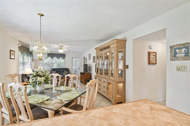 tiled dining room with plenty of natural light, a chandelier, a textured ceiling, and a ceiling fan