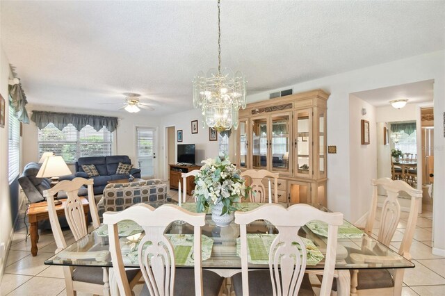 dining space with light tile patterned floors, ceiling fan, a textured ceiling, and a chandelier