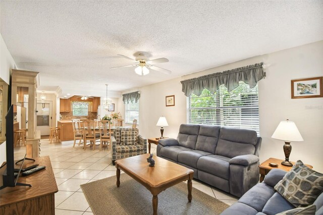 living room featuring a ceiling fan, light tile patterned flooring, and a textured ceiling