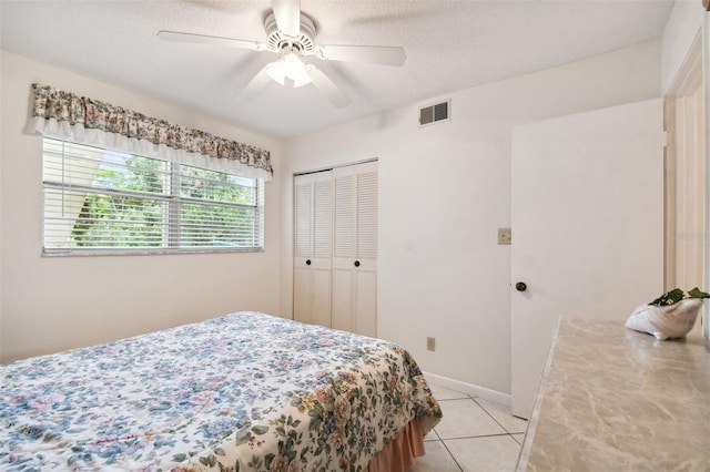 bedroom with a textured ceiling, ceiling fan, light tile patterned floors, and a closet