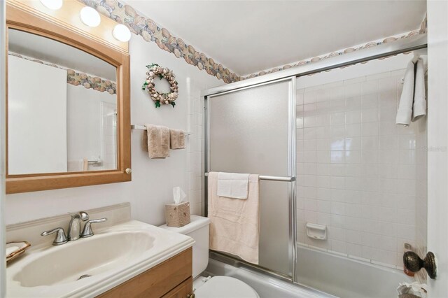 bathroom with vanity, bath / shower combo with glass door, and toilet