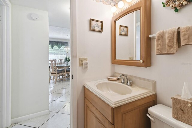 half bath featuring tile patterned flooring, toilet, and vanity