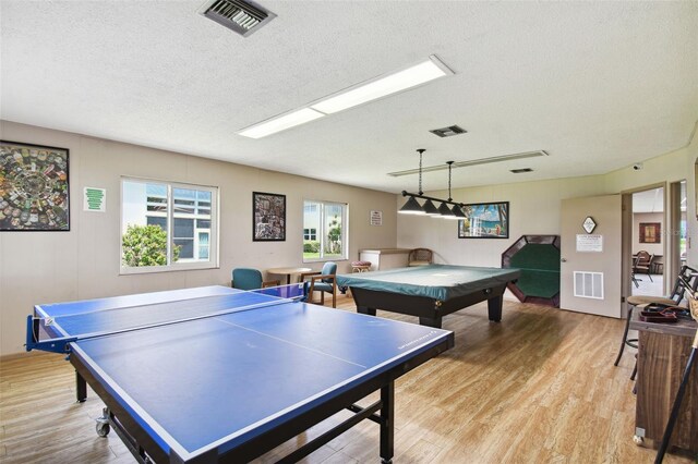 game room with a textured ceiling, light wood-style flooring, and billiards table