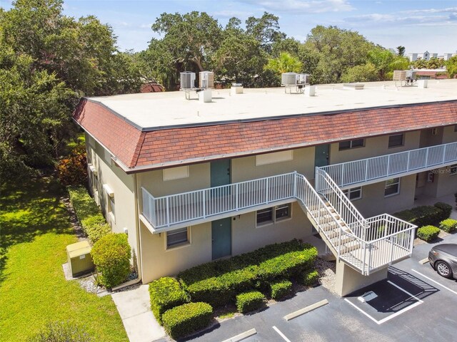 view of property with uncovered parking, stairs, and cooling unit