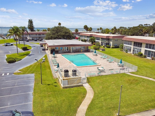 view of swimming pool featuring a water view, a lawn, and a patio