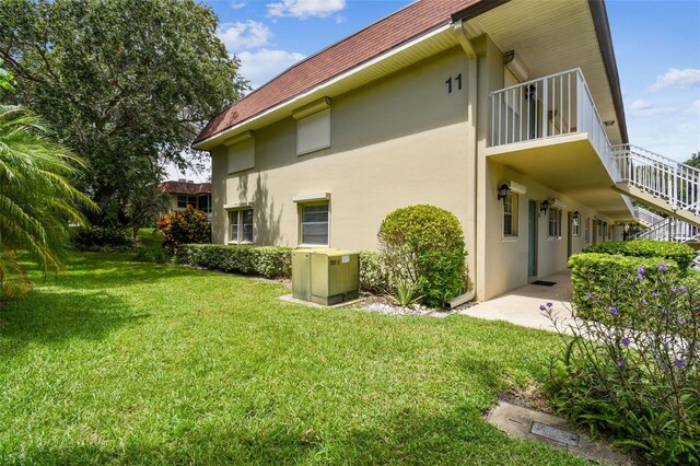 rear view of property featuring a lawn and stucco siding