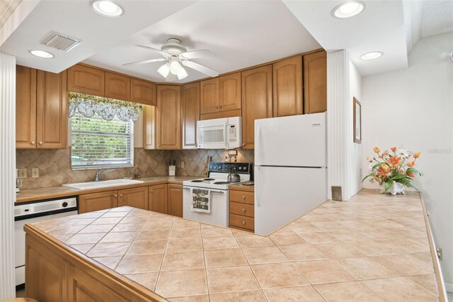 kitchen with white appliances, a sink, tile counters, decorative backsplash, and ceiling fan