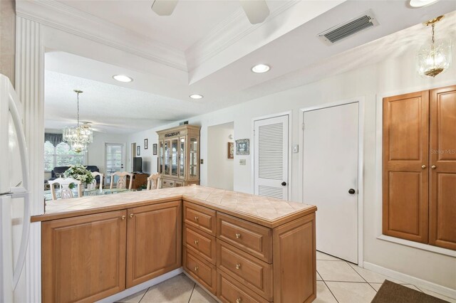 kitchen featuring tile counters, a chandelier, freestanding refrigerator, crown molding, and recessed lighting