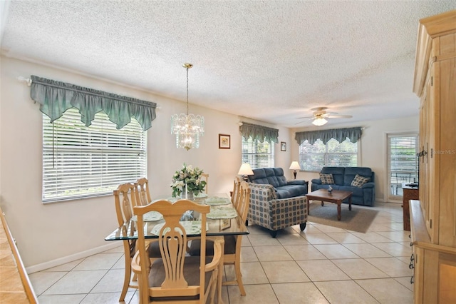 dining room featuring ceiling fan with notable chandelier, a textured ceiling, a healthy amount of sunlight, and light tile patterned floors