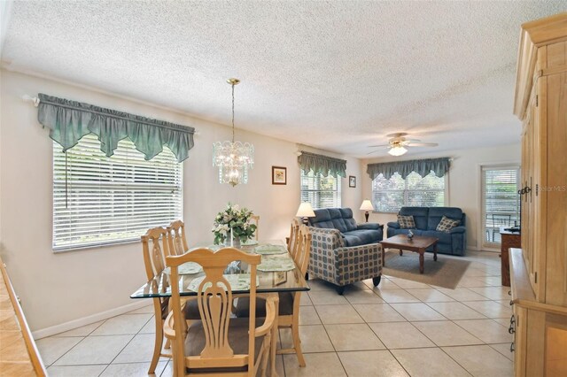dining area with a textured ceiling, light tile patterned floors, ceiling fan, a chandelier, and baseboards