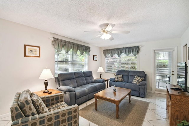 living room featuring ceiling fan, light tile patterned flooring, and a textured ceiling