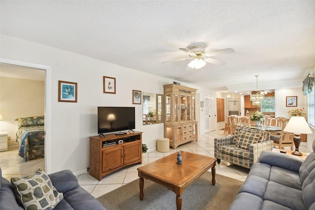 living room with ceiling fan with notable chandelier, light tile patterned floors, and a textured ceiling