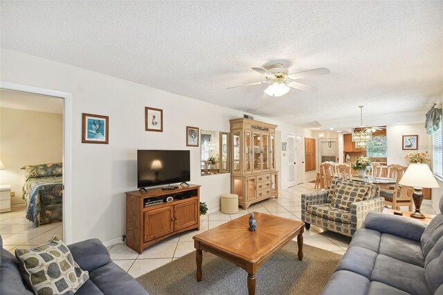 living room with light tile patterned floors, ceiling fan, a textured ceiling, and baseboards