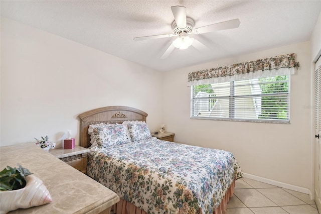 tiled bedroom with a textured ceiling, ceiling fan, and a closet