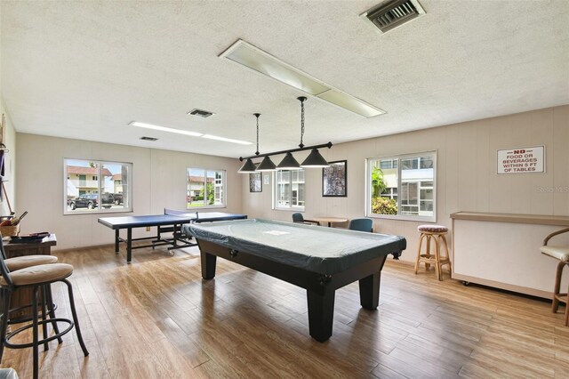 rec room featuring a textured ceiling, plenty of natural light, wood finished floors, and pool table