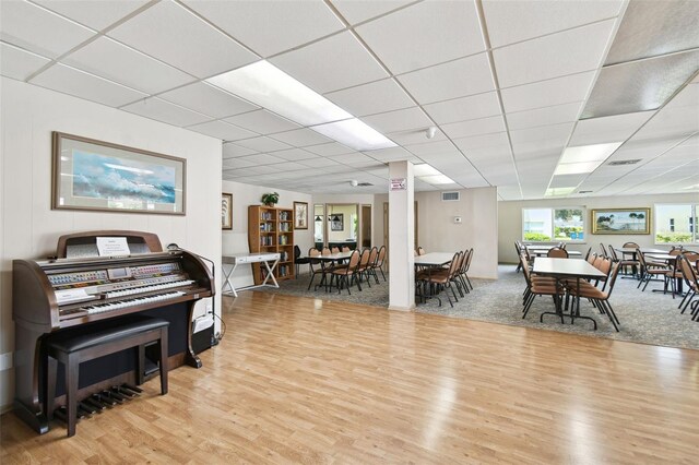 living area featuring light wood-type flooring and a drop ceiling