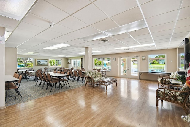 living room with plenty of natural light, a paneled ceiling, hardwood / wood-style floors, and french doors