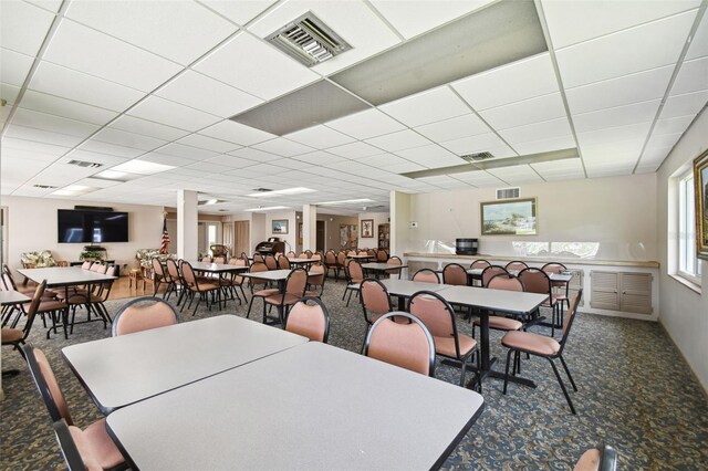 carpeted dining area with a paneled ceiling