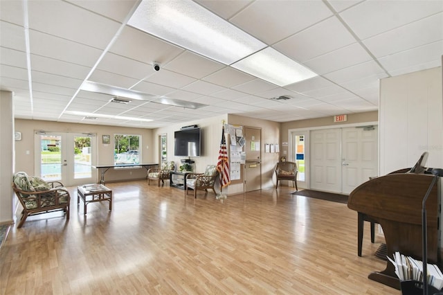 interior space with a paneled ceiling, wood-type flooring, and french doors