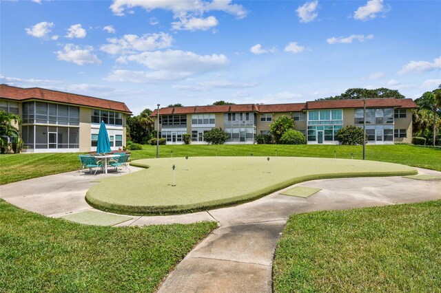 view of home's community with a putting green, a yard, and a patio