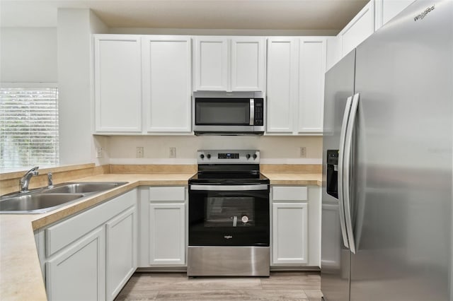 kitchen featuring sink, white cabinetry, stainless steel appliances, and light wood-type flooring