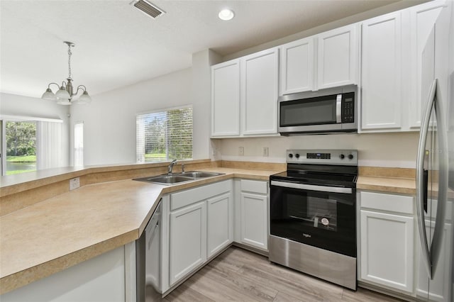 kitchen with appliances with stainless steel finishes, light hardwood / wood-style flooring, white cabinetry, and sink