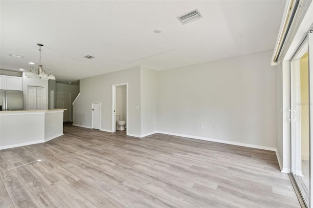 unfurnished living room featuring light hardwood / wood-style floors and a chandelier