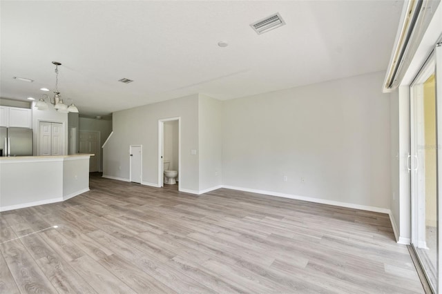 20461 Berrywood Ln, Tampa, FL 33647 - unfurnished living room featuring a notable chandelier, baseboards, visible vents, and light wood-style flooring