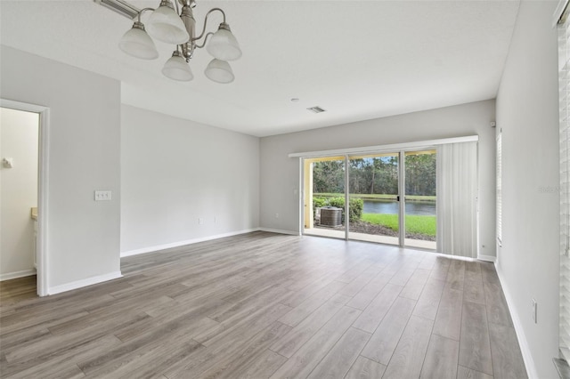 empty room featuring light hardwood / wood-style flooring and a chandelier