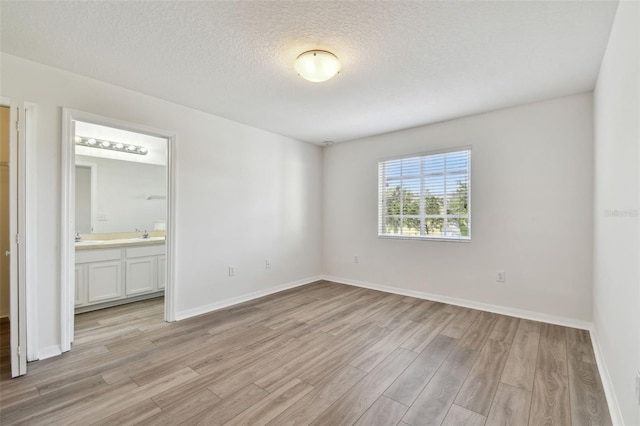 empty room featuring a textured ceiling, sink, and light wood-type flooring