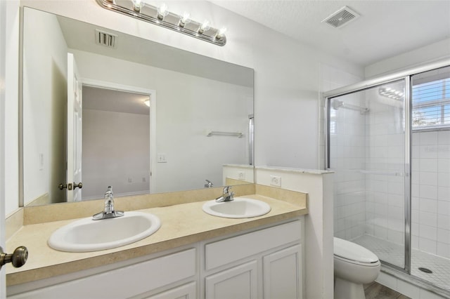 bathroom with vanity, a shower with shower door, and toilet