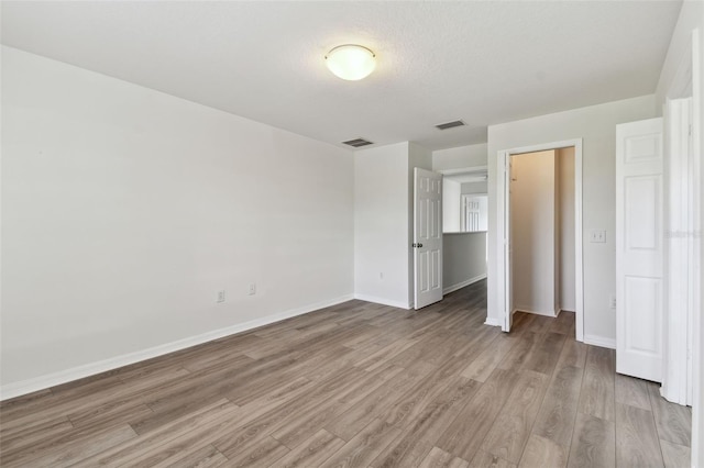 unfurnished bedroom featuring light hardwood / wood-style flooring, a textured ceiling, and a closet