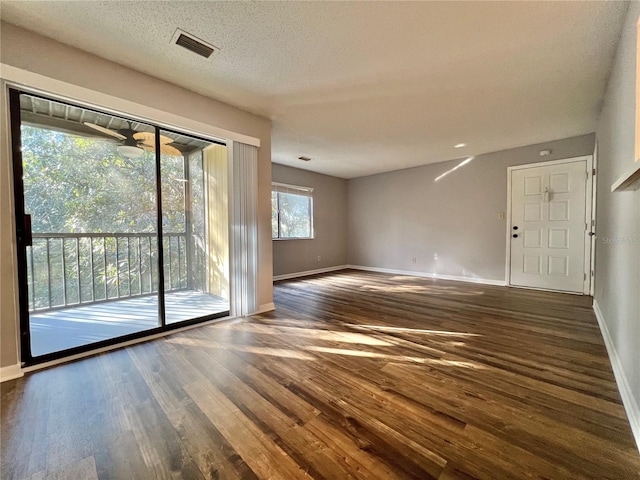 spare room featuring a textured ceiling and dark hardwood / wood-style flooring