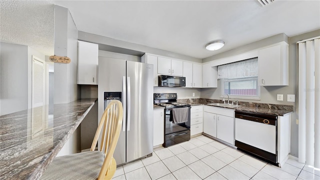 kitchen with sink, black appliances, dark stone countertops, white cabinetry, and light tile patterned flooring