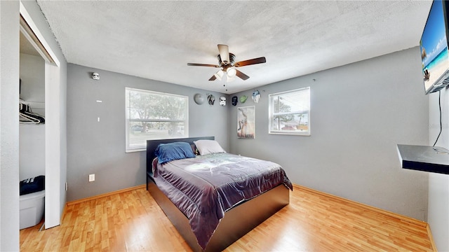 bedroom with ceiling fan, hardwood / wood-style floors, and a textured ceiling