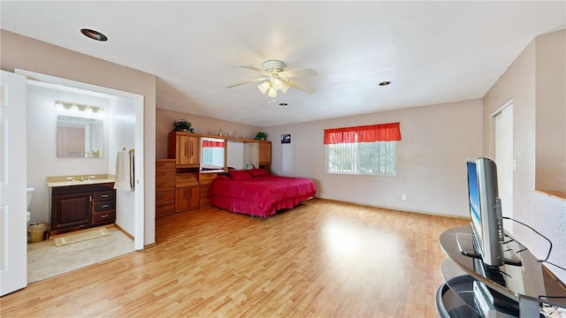 bedroom featuring connected bathroom, light hardwood / wood-style flooring, ceiling fan, and sink