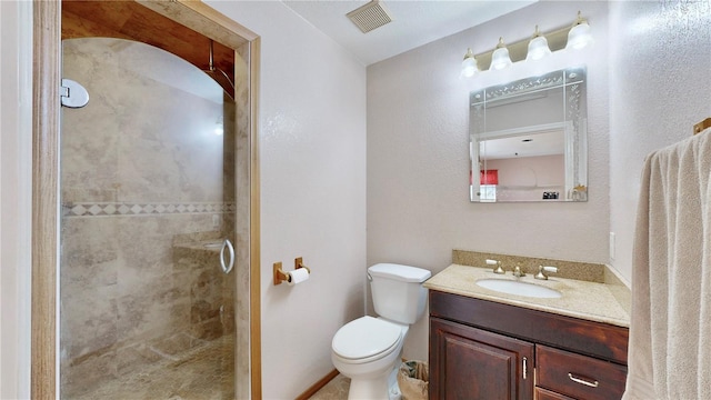 bathroom with a tile shower, vanity, and toilet